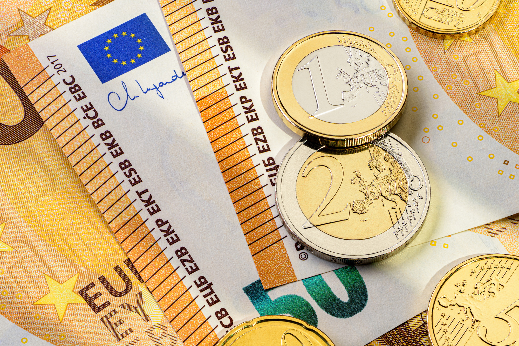 Fifty euro banknotes and different coins on a flat surface.